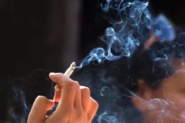 Eine Hand, die eine rauchende Zigarette hält
